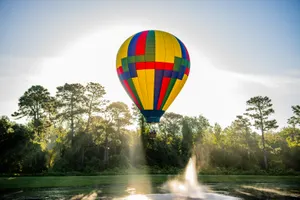 Hot Air Balloon flying over water fountain.