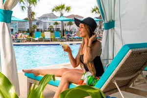 Woman holding a margarita in a poolside cabana