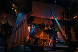 Indoor arena of galleon pirate ship and lagoon with ship's sails hoisted above the audience and performers.