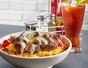 Available all day, this popular dish contains seasoned sirloin steak, scrambled eggs, and roasted grape tomatoes served over hashbrowns and drizzled with Hollandaise sauce.