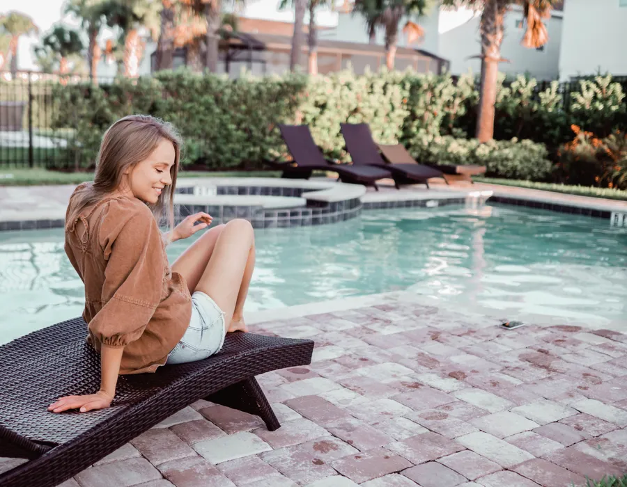 Woman on a chair in the backyard next to the pool.