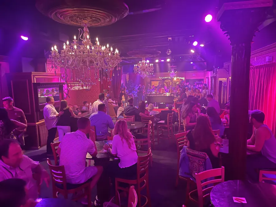 Tables and chairs with dueling pianos and bar