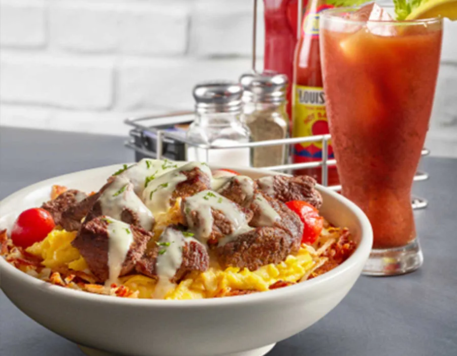 Available all day, this popular dish contains seasoned sirloin steak, scrambled eggs, and roasted grape tomatoes served over hashbrowns and drizzled with Hollandaise sauce.
