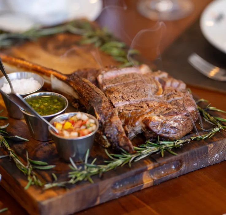 32 oz Fire-roasted Tomahawk steak served with 3 sides
